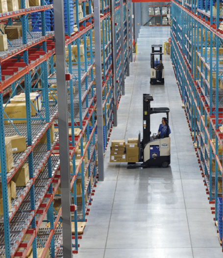 A stocked warehouse with a driven forklift in a long aisle
